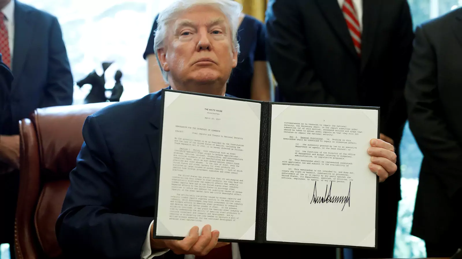 U.S. President Donald Trump holds up a directive ordering an investigation into the impact of foreign steel on the American economy after signing it.