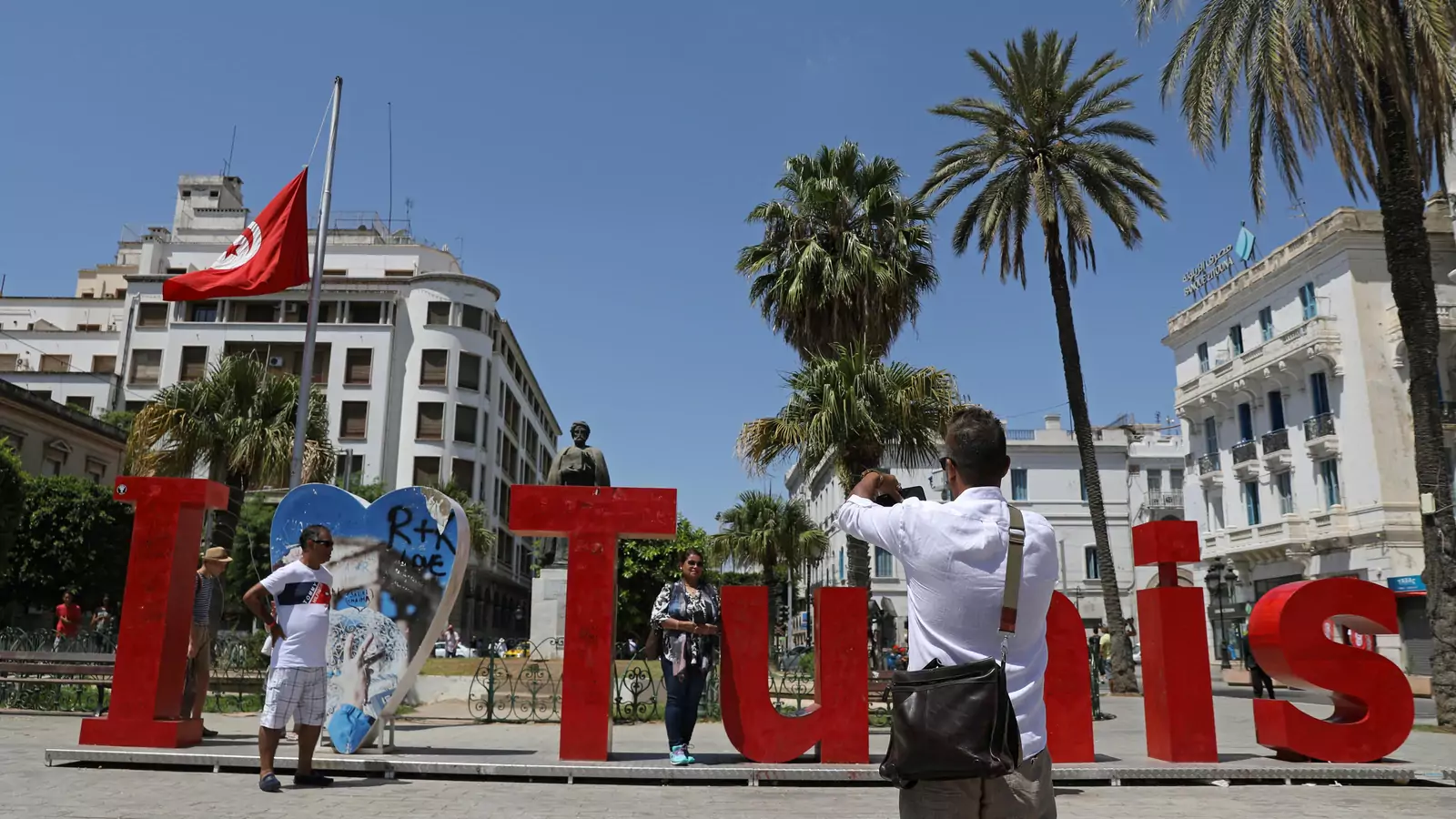 People pose for a photo with "I love Tunis" sign as a Tunisian flag flies at half-mast in honor of late Tunisian President Beji Caid Essebsi, in Tunis, Tunisia July 28, 2019.