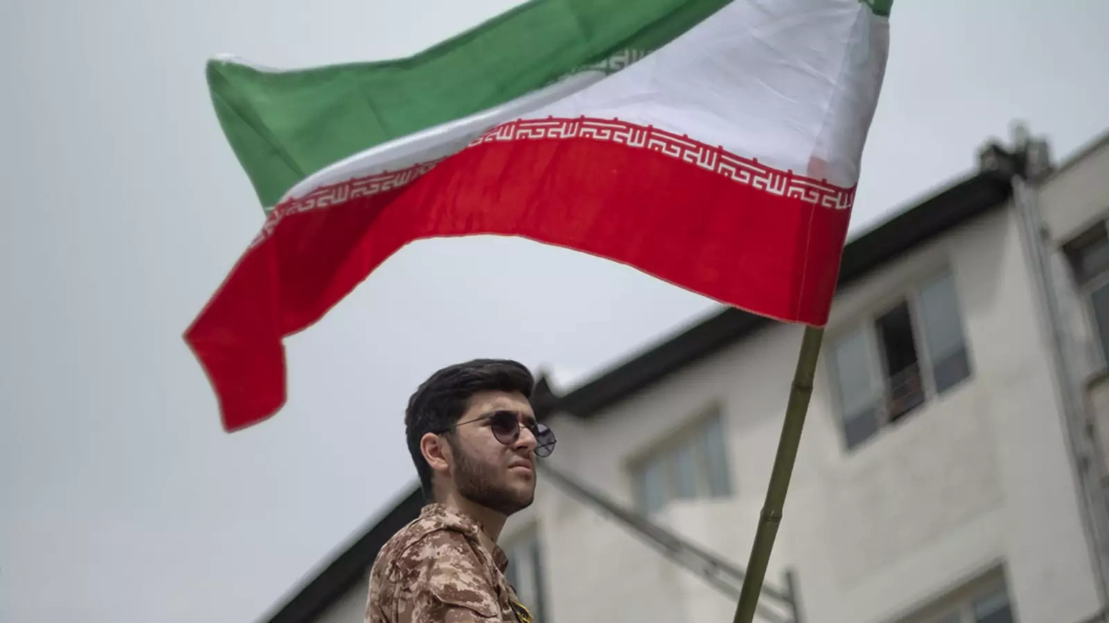 A member of the Islamic Revolutionary Guard Corps waves the Iranian flag during a rally in downtown Tehran.
