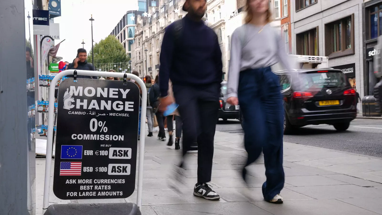 People walk past a sign outside a currency exchange office in London.