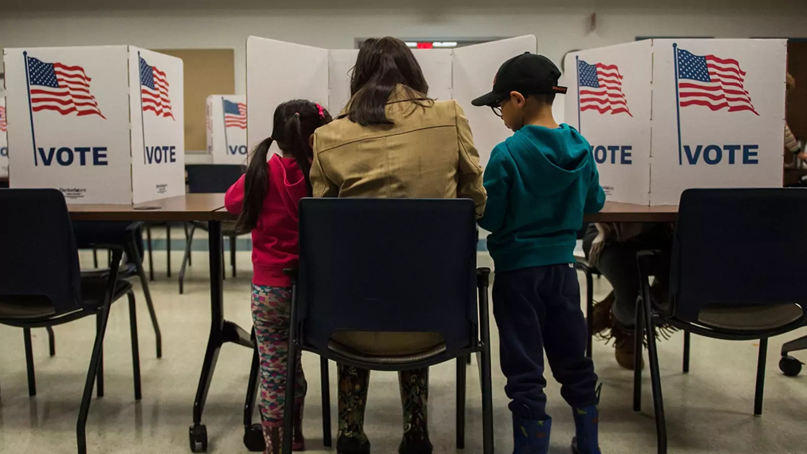 A woman and her children vote at a polling station during the mid-term elections at the Fairfax County bus garage in Lorton, Virginia on November 6, 2018.