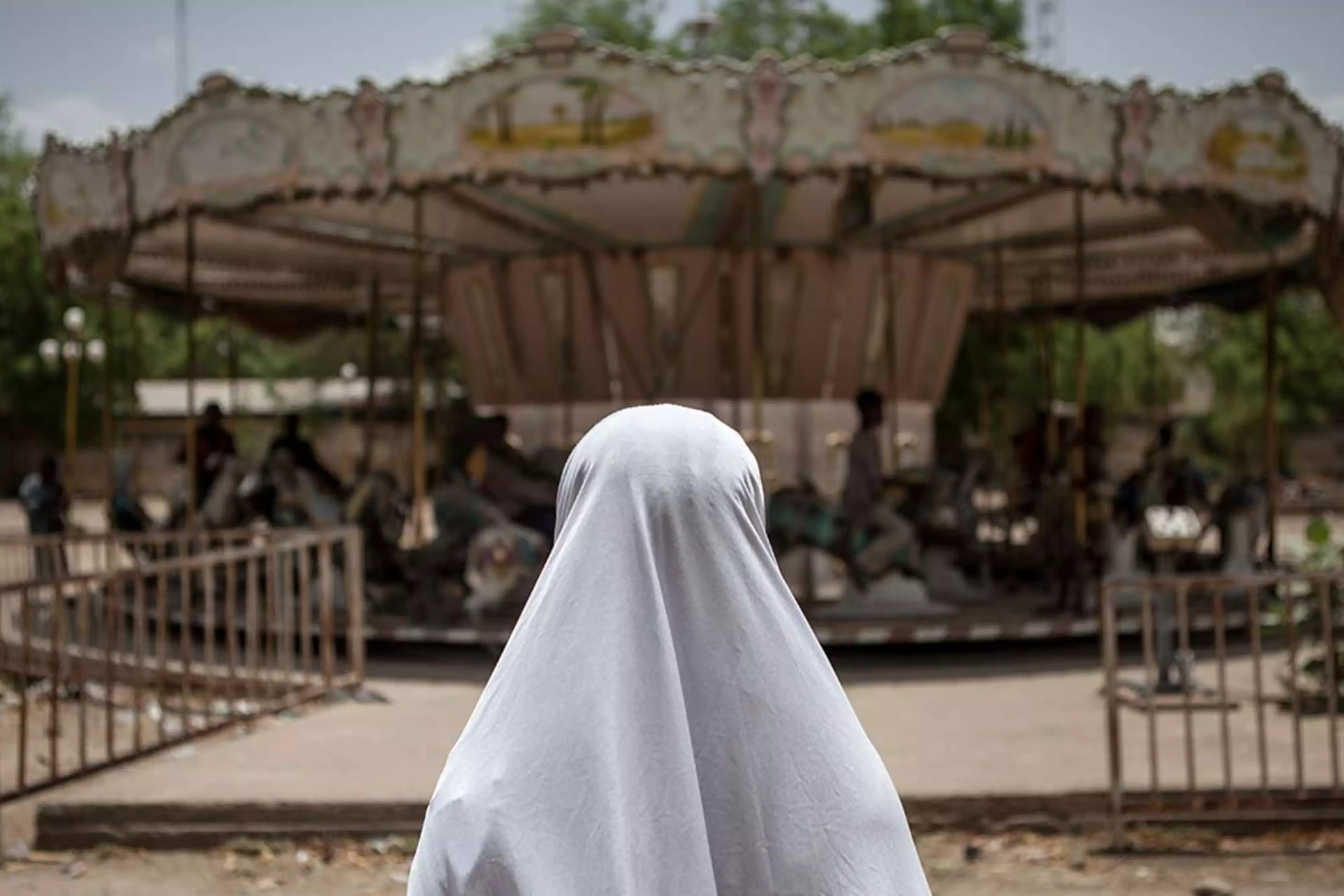 A girl watches a merry-go-round at an abandoned amusement park in Maiduguri, Nigeria.