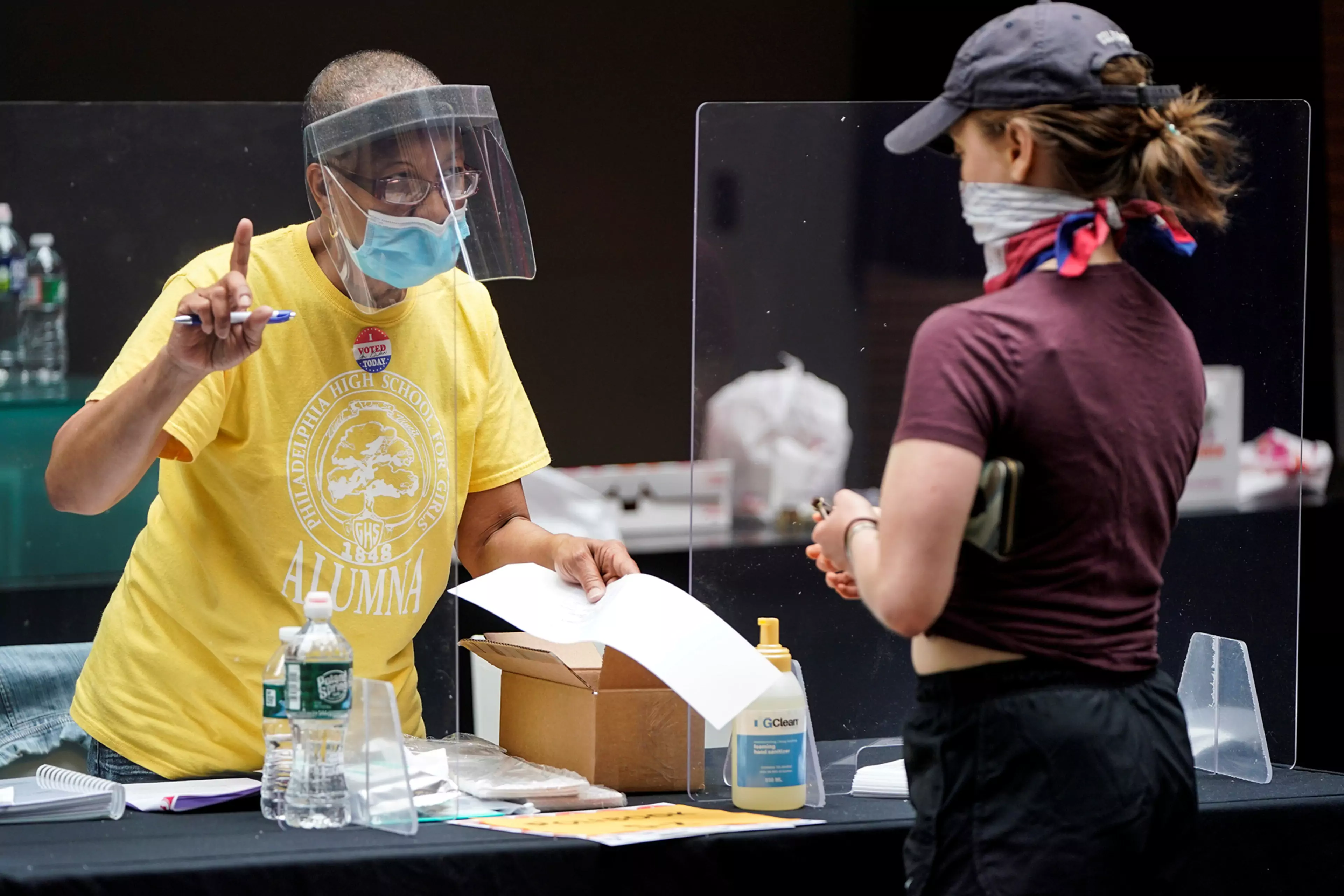 A poll worker and voter wear masks to prevent the spread of COVID-19 during a U.S. primary election.