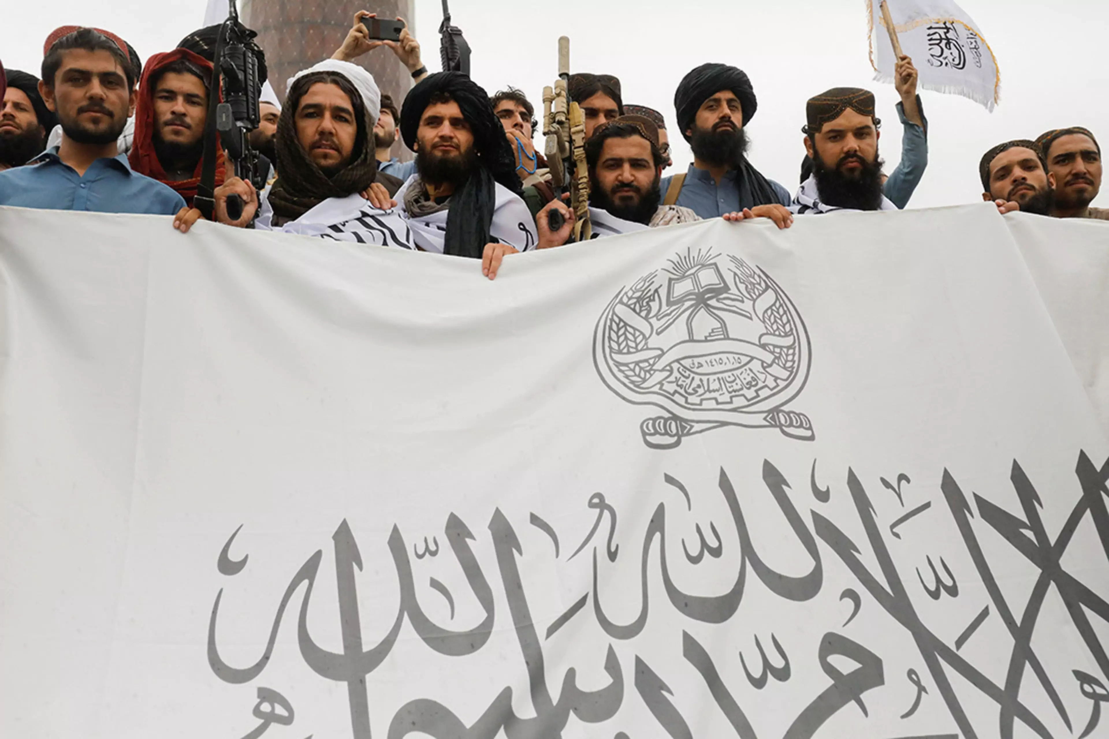 Taliban fighters hold a flag for the Islamic Emirate of Afghanistan in August 2022. 