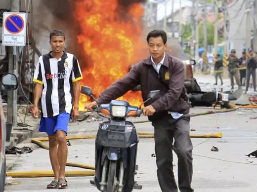 People leave the scene after a car bomb exploded in southern Thailand's Sai Buri district.