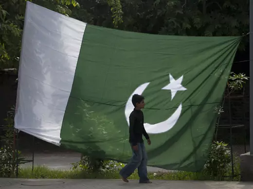 A boy walks past a Pakistani flag in Rawalpindi (Faisal Mahmood/Courtesy Reuters).