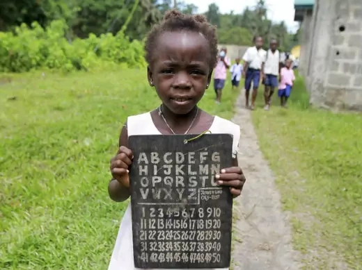 A girl holds a slate with alphabets and numbers along a path in the Koluama village in Nigeria's Bayelsa state May 15, 2012.