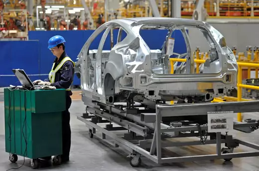 An employee uses a laptop next to a car body at an assembly line at a Ford manufacturing plant in Chongqing municipality April 20, 2012. 