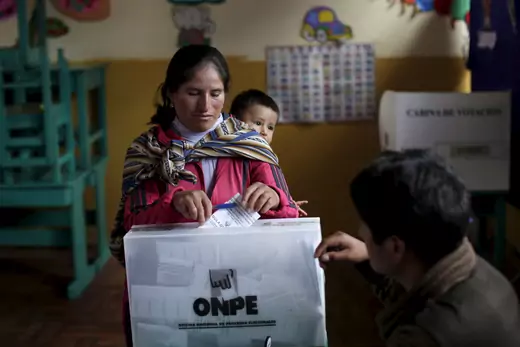 A woman carrying her child casts her vote during general elections in the district of Poroy in Cuzco, April 10, 2016.