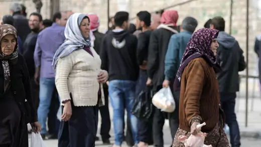Syrian women hold food aid distributed by humanitarian institutions.