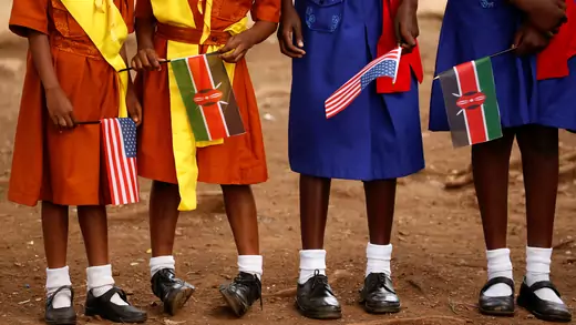 Girls with U.S. and Kenya flags wait to greet U.S. Ambassador to Kenya as he visits a President's Emergency Plan for AIDS Relief (PEPFAR) project for girls' empowerment in Nairobi, Kenya.