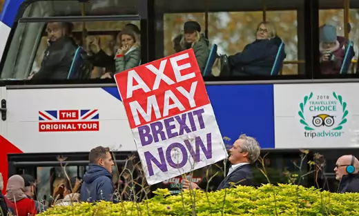 A pro-Brexit campaigner holds a placard as a tourist bus passes by in Westminster London.