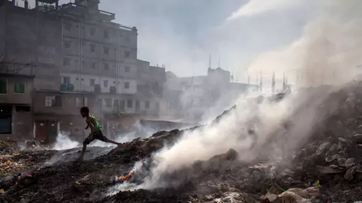 A child runs beside the waste-burning area of a dump in Dhaka, Bangladesh.