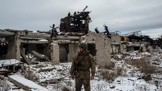 A Ukrainian Army soldier stands in front of destroyed buildings on the front line.