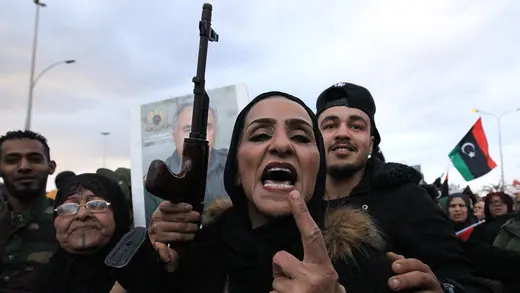 A woman in black holds a gun during in a demonstration