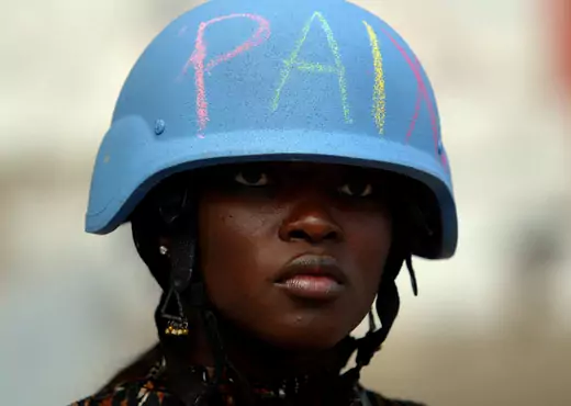 A U.N. worker wears a U.N. helmet with the word "peace" written on it in Martissant, Haiti.