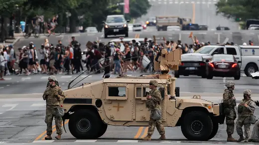 A military vehicle passes behind law enforcement personnel as protesters rally against the death of George Floyd, near the White House in Washington, DC, June 3, 2020. 
