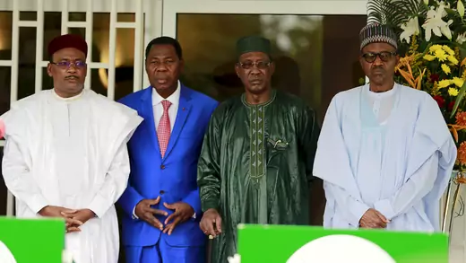 Four heads of state pose for a photo. From left to right, the president of Niger in a white Nigerien boo boo (long robe) with a maroon cap. The president of Benin in a royal blue suit with a salmon tie and white shirt. The president of Chad in a dark green tunic with a cap, and the president of Nigeria in a powder blue boubous (billowy robe), with a green embroidered cap.
