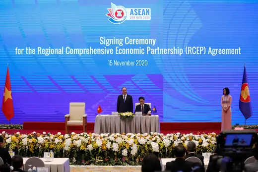 Vietnam's Industry and Trade Minister Tran Tuan Anh (C) signs as Vietnam's Prime Minister Nguyen Xuan Phuc (L) witnesses during the signing ceremony of the Regional Comprehensive Economic Partnership (RCEP) Agreement during the 37th ASEAN Summit in Hanoi, Vietnam on November 15, 2020.