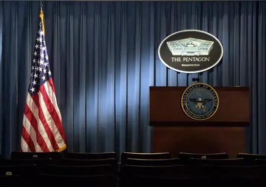 The Pentagon logo and an American flag are lit up January 3, 2002 in the briefing room of Pentagon in Arlington, VA.