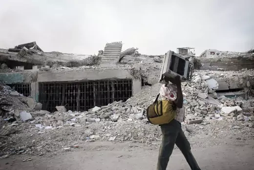 Teenage boy carrying a typewriter by rubble