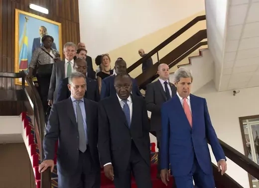 A group of officials walk down a staircase in professional dress.