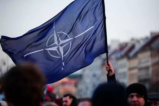 A man holds a NATO flag near the Royal Castle ahead of a speech by US president Joe Biden on March 26, 2022 in Warsaw, Poland.