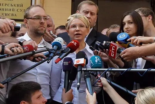 Former Prime Minister Yulia Tymoshenko is seen outside the court surrounded by microphones from journalists.