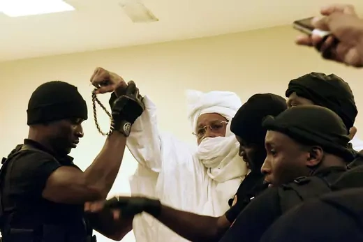 Prison guards escort former Chadian dictator Hissene Habre  into the courtroom for his trial