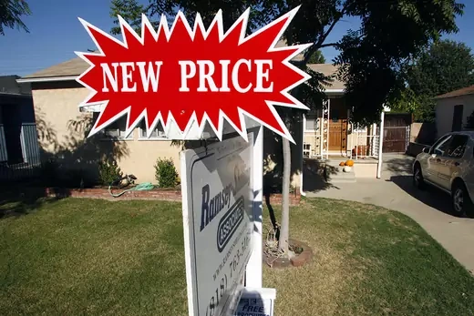 Photo showing a real estate for sale sign with "New Price" sign affixed to it.
