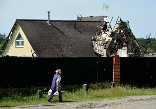 An elderly woman walks past a building partialy destroyed by shelling in the village of Moshchun, Kyiv region, on June 2, 2022 on the 99th day of the Russian invasion of Ukraine.