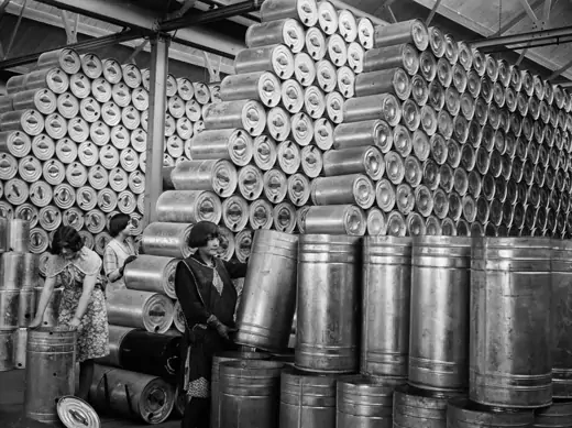 Workers at a factory stacking drums of oil in a warehouse, 1930.