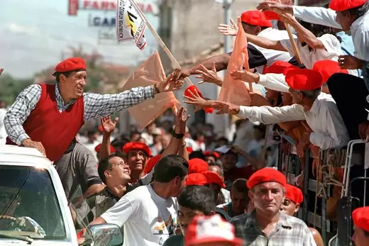 Hugo Chavez wearing a red beret is seen greeting supporters who are also wearing red berets.