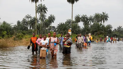 People wade through knee-deep water in Nigeria.