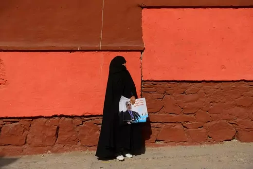 An Afghan woman carries posters of presidential candidate Abdullah Abdullah ahead of elections set for September 2019.