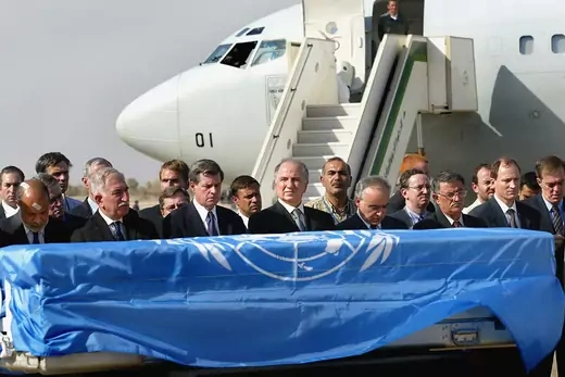 Officials, including Paul Bremer and Ahmed Chalabi, stand before the coffin of slain UN envoy to Iraq Sergio Vieira de Mello during a ceremony, before the coffin was put on a Brazilian airforce jet.