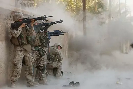 Marines use explosives and machine guns to open a metal gate to a house, as they search houses for insurgents in Fallujah, Iraq.