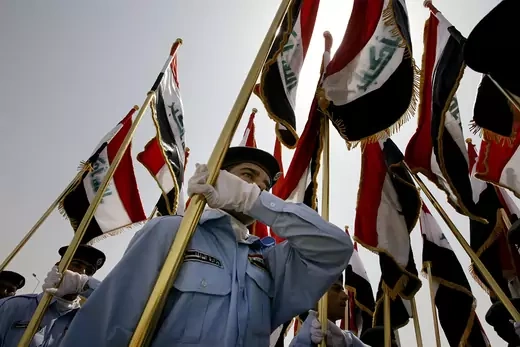 Iraqi security forces carry Iraqi flags as they parade during a handover ceremony.