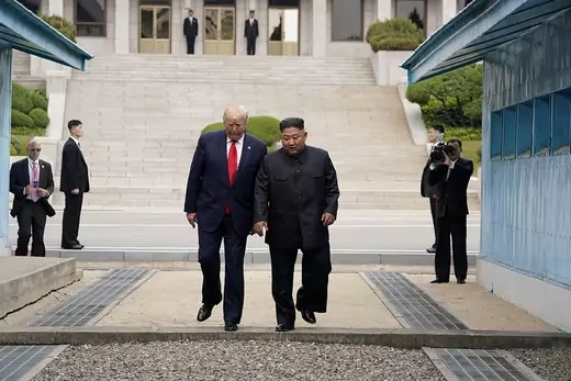 Trump and Kim stand next to each other and step over the line separating North Korea and South Korea at the DMZ.