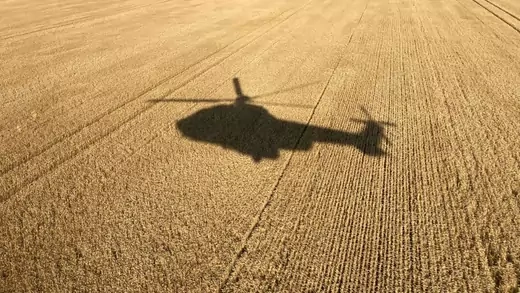 Helicopter flying over a wheat field.