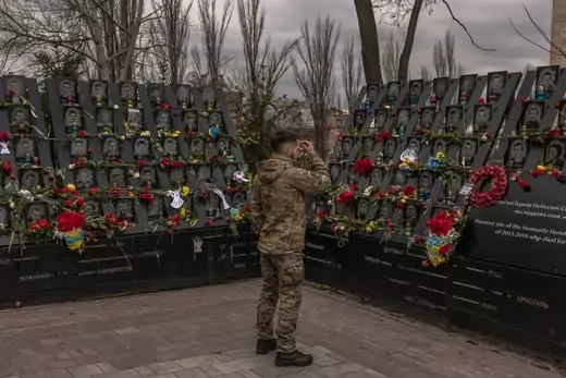 A Ukrainian serviceman crosses himself in front of the memorial to the Heavenly hundred heroes, who were killed in 2014 during the mass Euromaidan protests, on the Day of Remembrance of Heroes of Heavenly Hundred, on February 20, 2023 in Kyiv, Ukraine