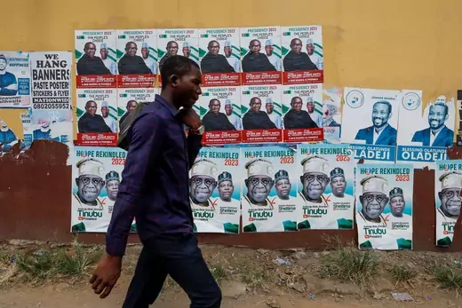 A man walks by a wall of election campaign posters in Nigeria. 