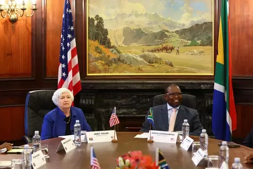In front of the flags of the United States and the Republic of South Africa, U.S. Treasury Secretary Janet Yellen and South Africa's Finance Minister Enoch Godongwana sit at the head of a table for a bilateral meeting in Pretoria, South Africa.