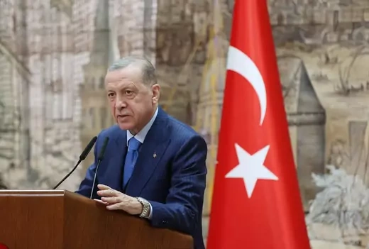 Turkish President, Recep Tayyip Erdoğan in a blue suit speaking at a podium 