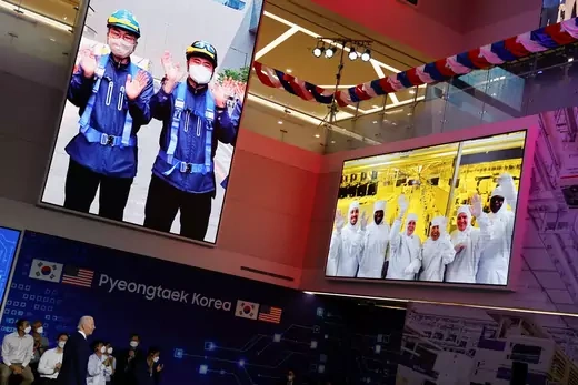 Samsung employees are displayed on screens as they gesture during U.S. President Joe Biden's visit to a semiconductor factory at the Samsung Electronics Pyeongtaek Campus in Pyeongtaek, South Korea
