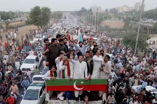 Former Prime Minister Imran Khan as viewed standing on top of a vehicle surrounded by protesters.