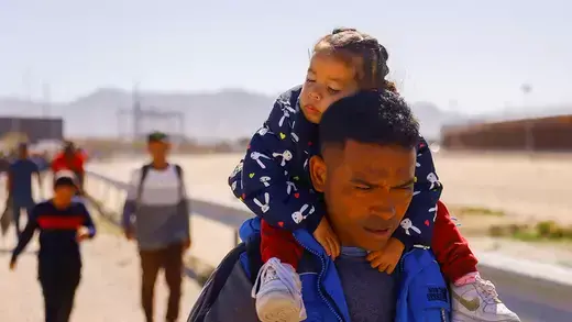 Asylum seeker at U.S. southern border carries young girl on his shoulders