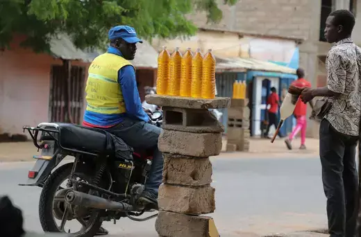 A man on a motorcycle is pictured wearing a yellow vest near five bottles of smuggled fuel.