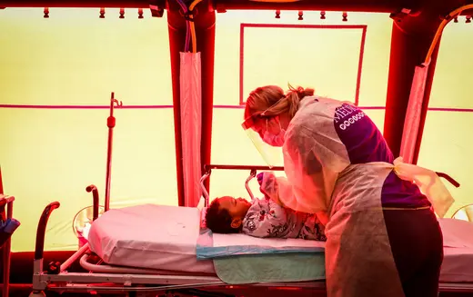 A Boston Medical Center child life specialist tends to a baby in a pediatrics tent.