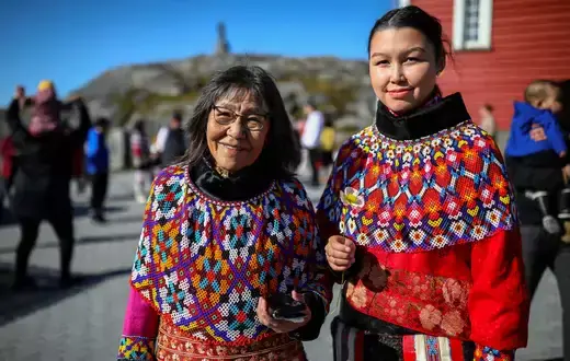 A young and an old woman in traditional Inuit clothing stand after a baptism in front of the Nuuk Cathedral (Church Of Our Saviour) in Nuuk, Greenland, September 5, 2021